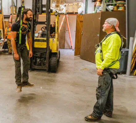 Man hanging by safety harness from forklift during training