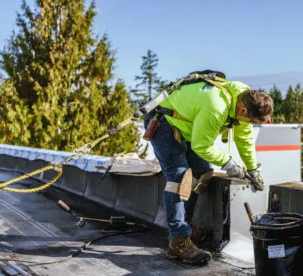 Man roofing while wearing safety harness